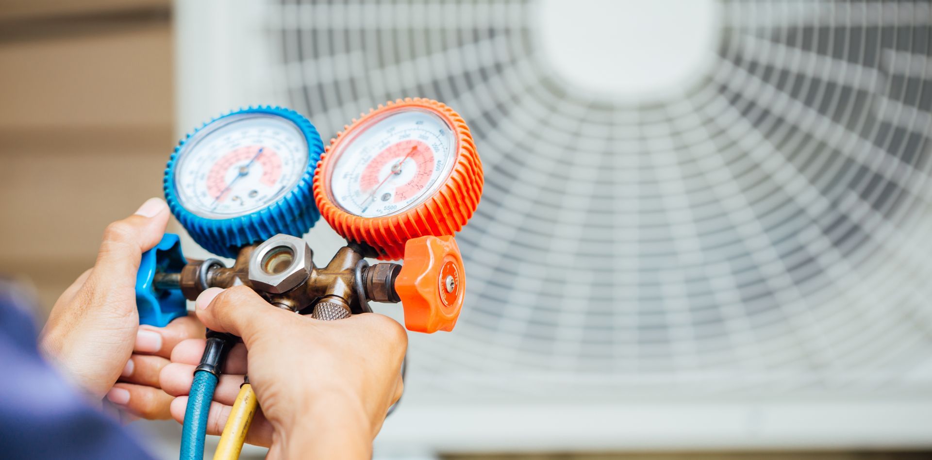a person is holding a couple of gauges in front of an air conditioner .