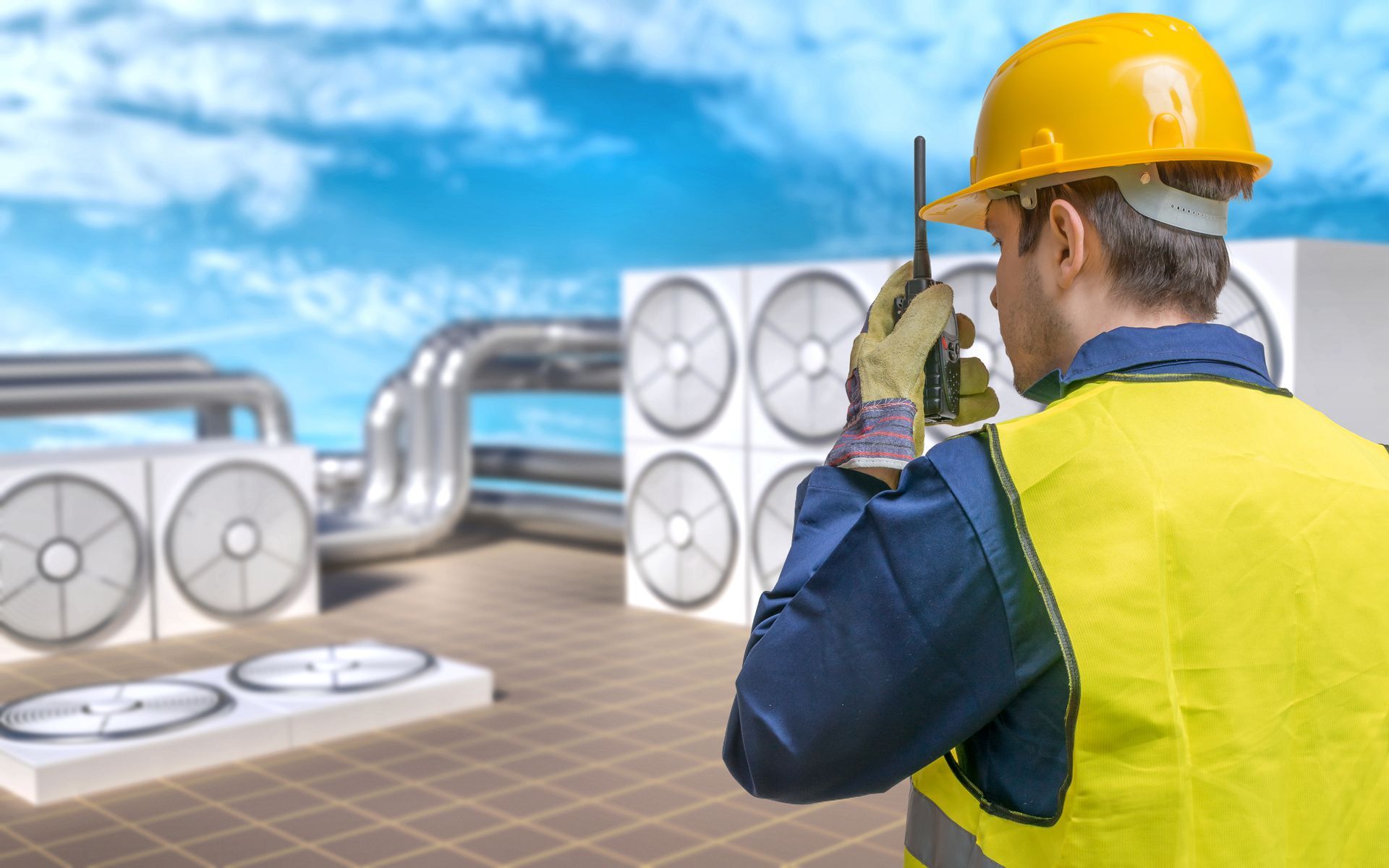 a man wearing a hard hat and safety vest is talking on a walkie talkie .