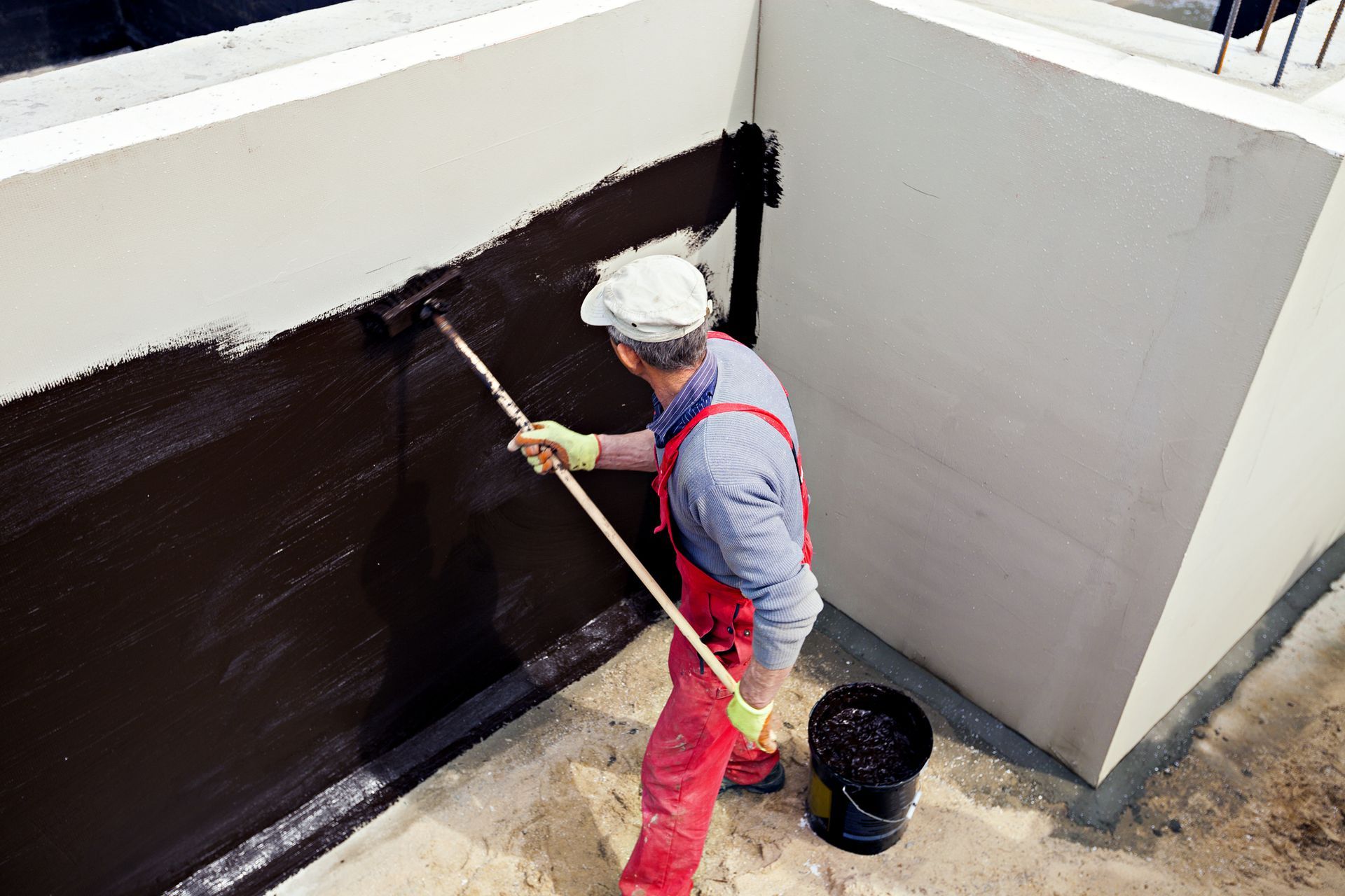 a man is painting a wall with a roller .
