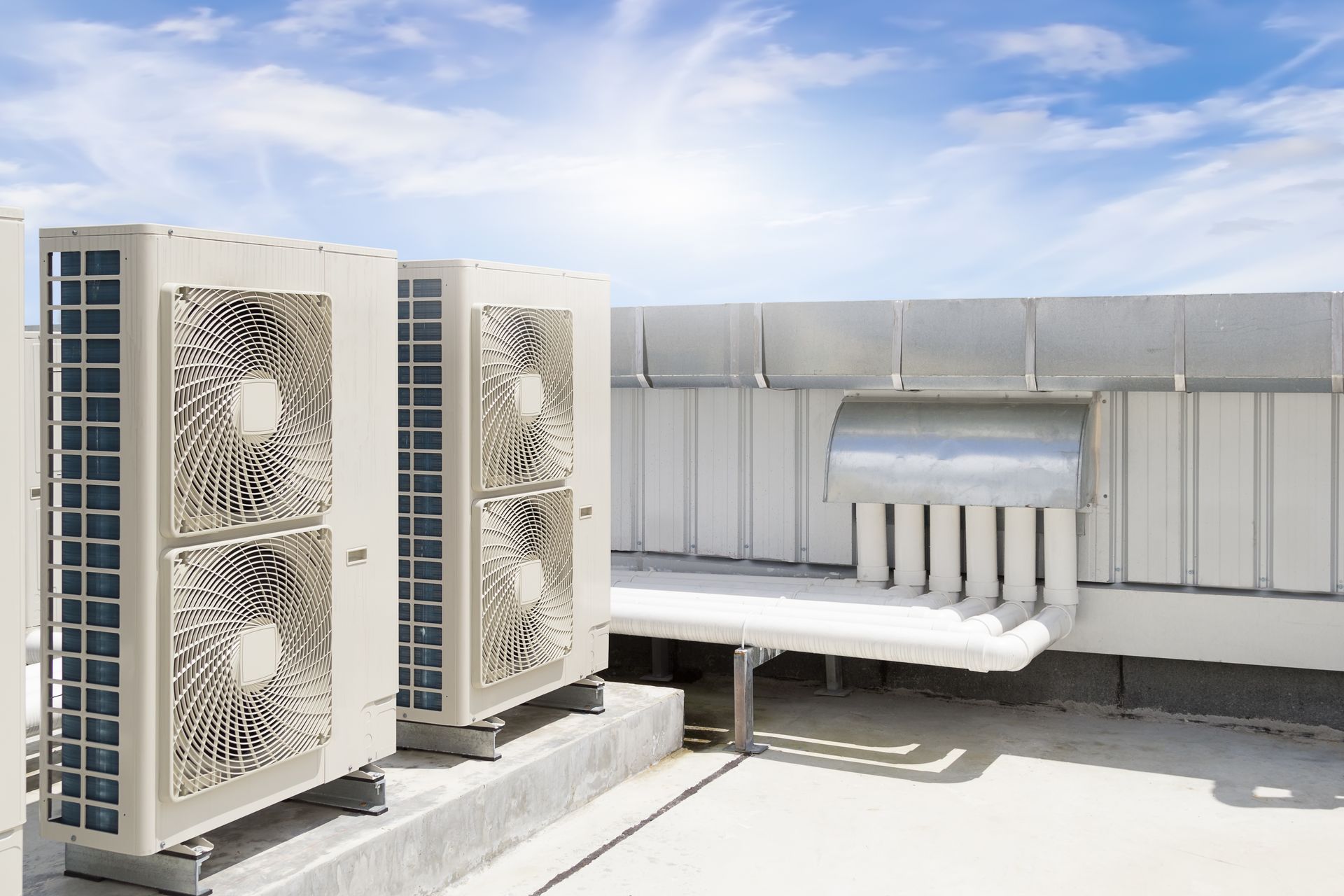 there are two air conditioners on the roof of a building .