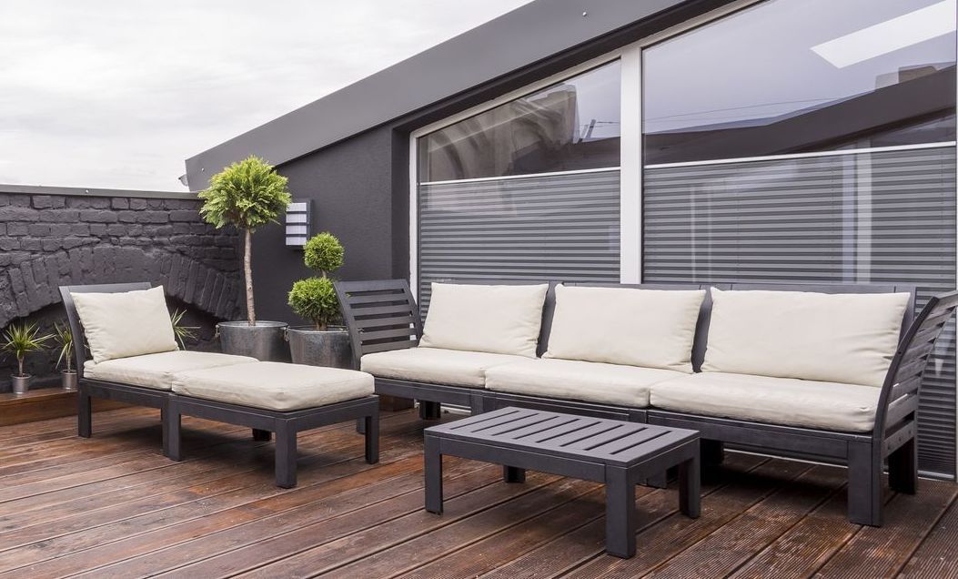 a patio with a couch , chairs , and a table on a wooden deck .