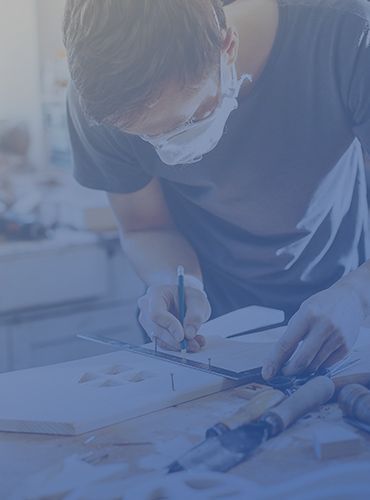 a man wearing a mask is working on a piece of wood .