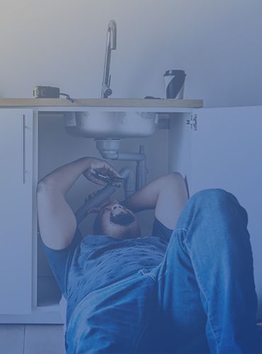 a man is laying on the floor fixing a sink in a kitchen .