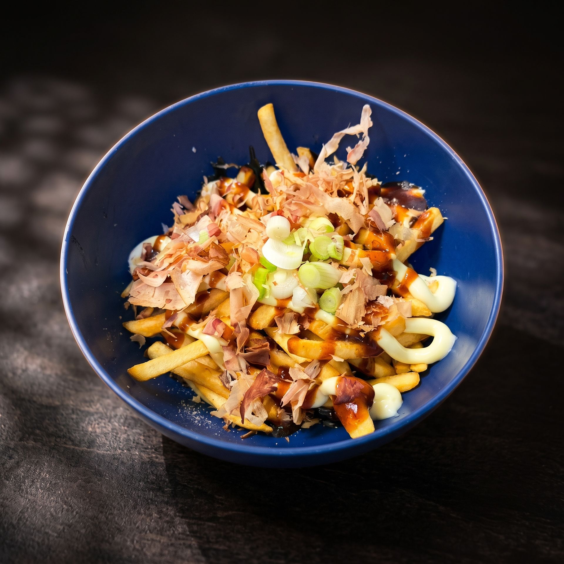 Blue bowl of fries topped with shredded meat and diced green onions