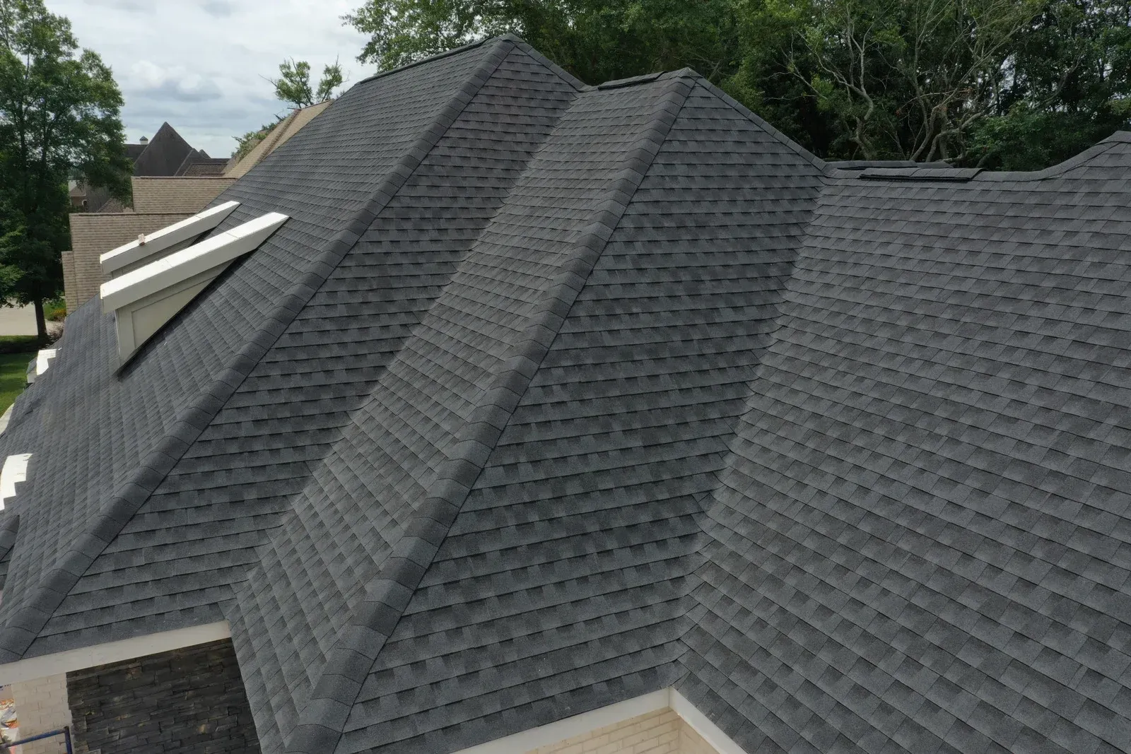 Dark gray asphalt shingle roof on a house with multiple roof planes.
