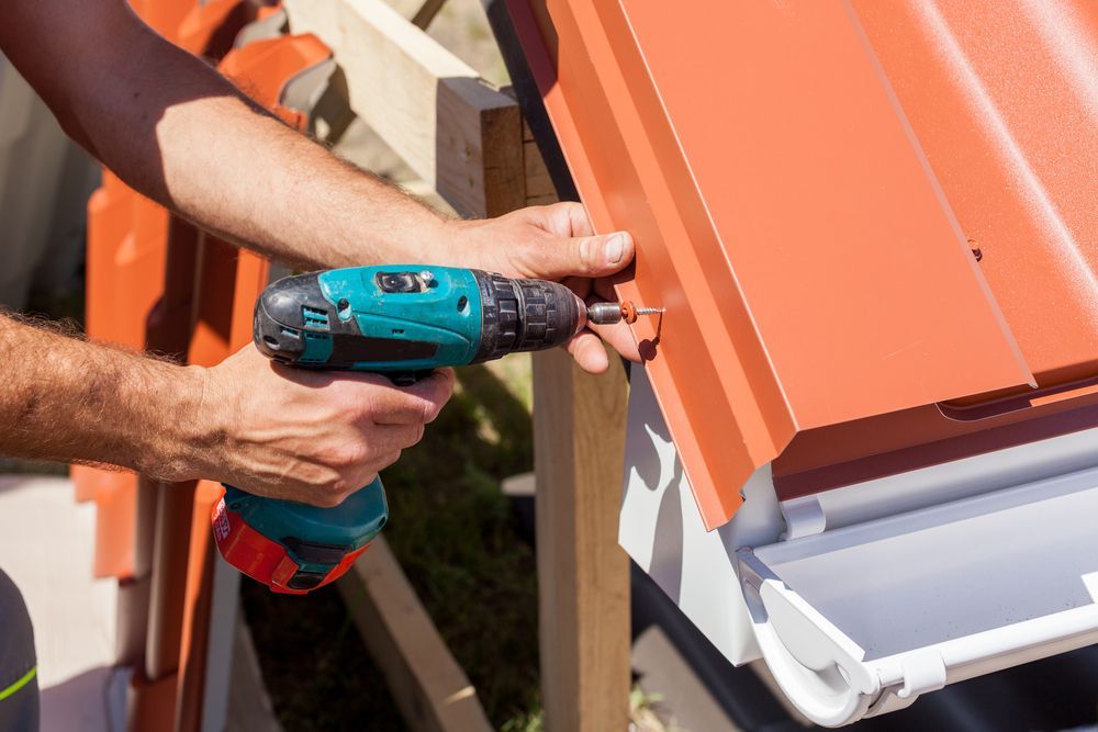 A Man Is Working On A Roof With A Drill — Sattin's Metal Roofing In Kiama, NSW