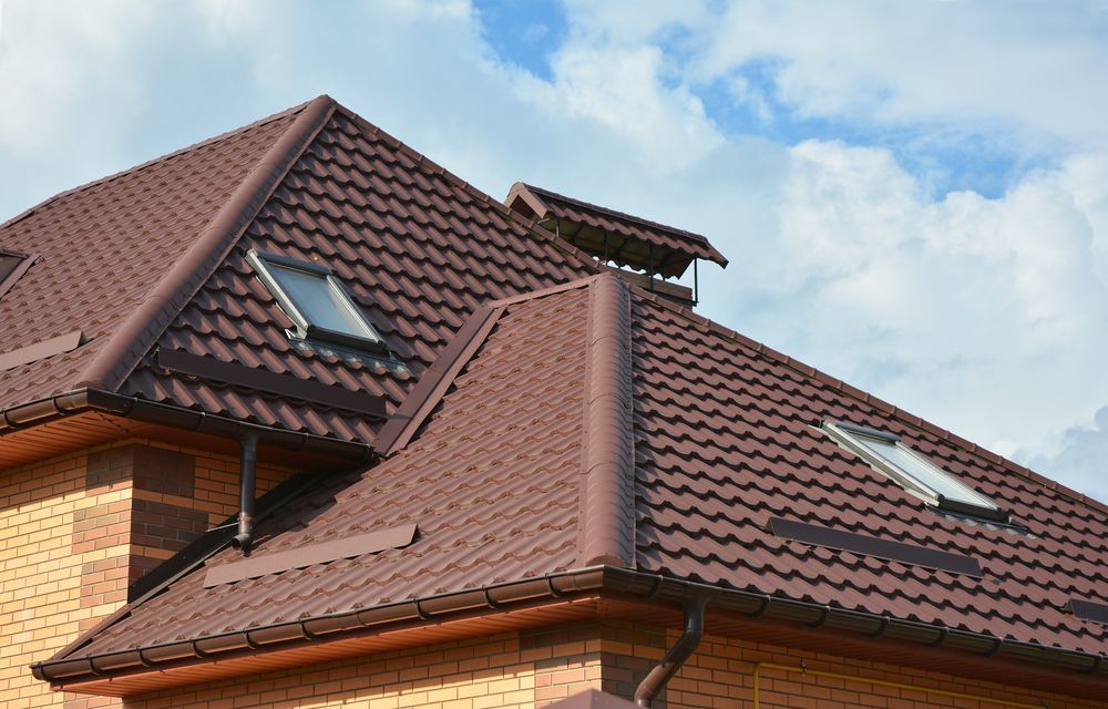 A Brick House With A Brown Roof And Two Skylights — Sattin's Metal Roofing In Shellharbour, NSW