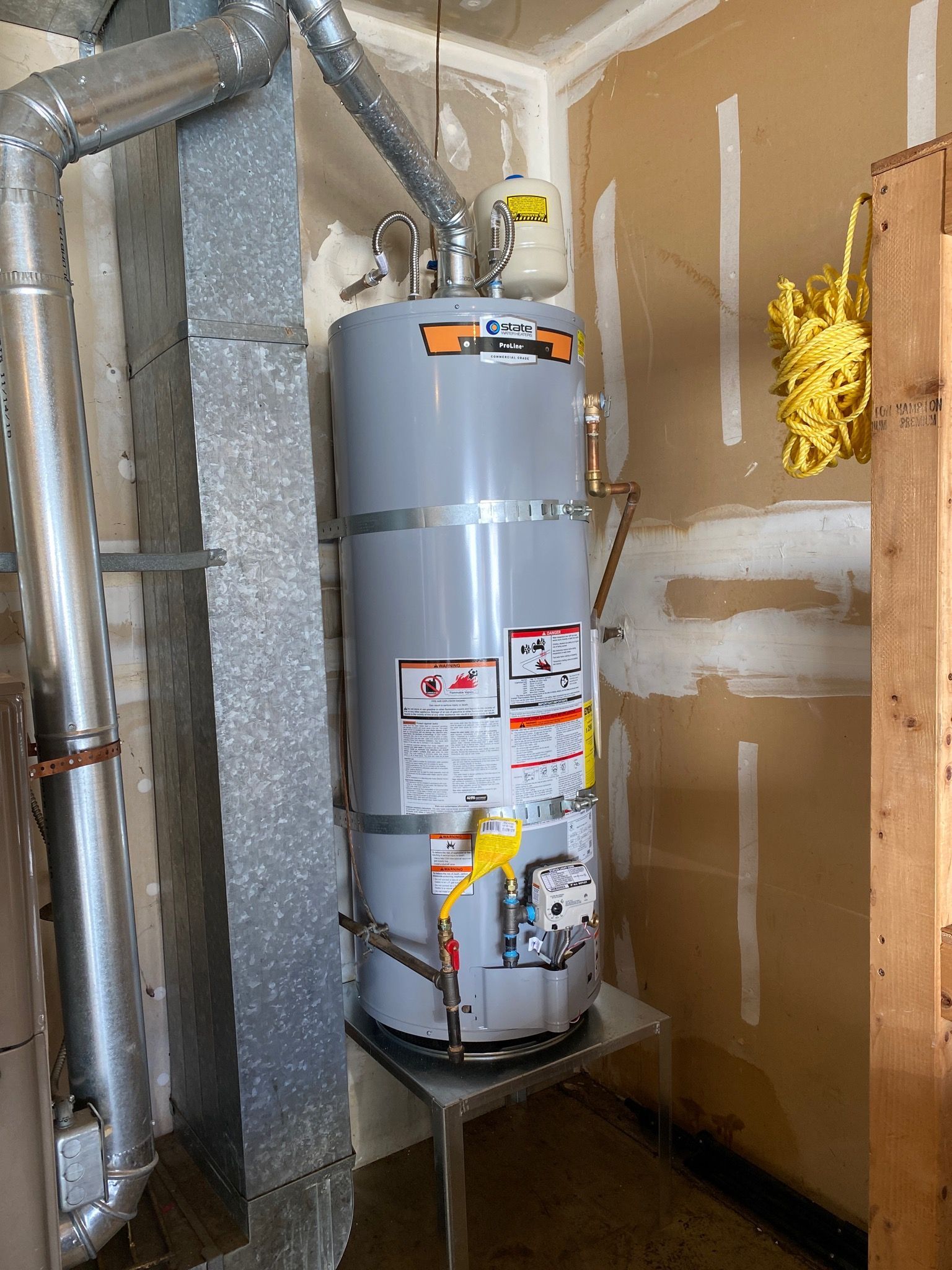 Gray water heater with metal pipes in a utility room.