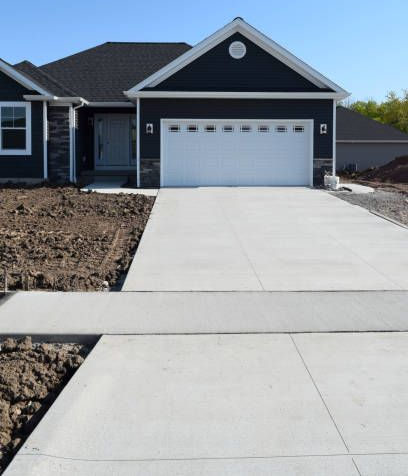 Suburban house with a white garage and newly poured concrete driveway