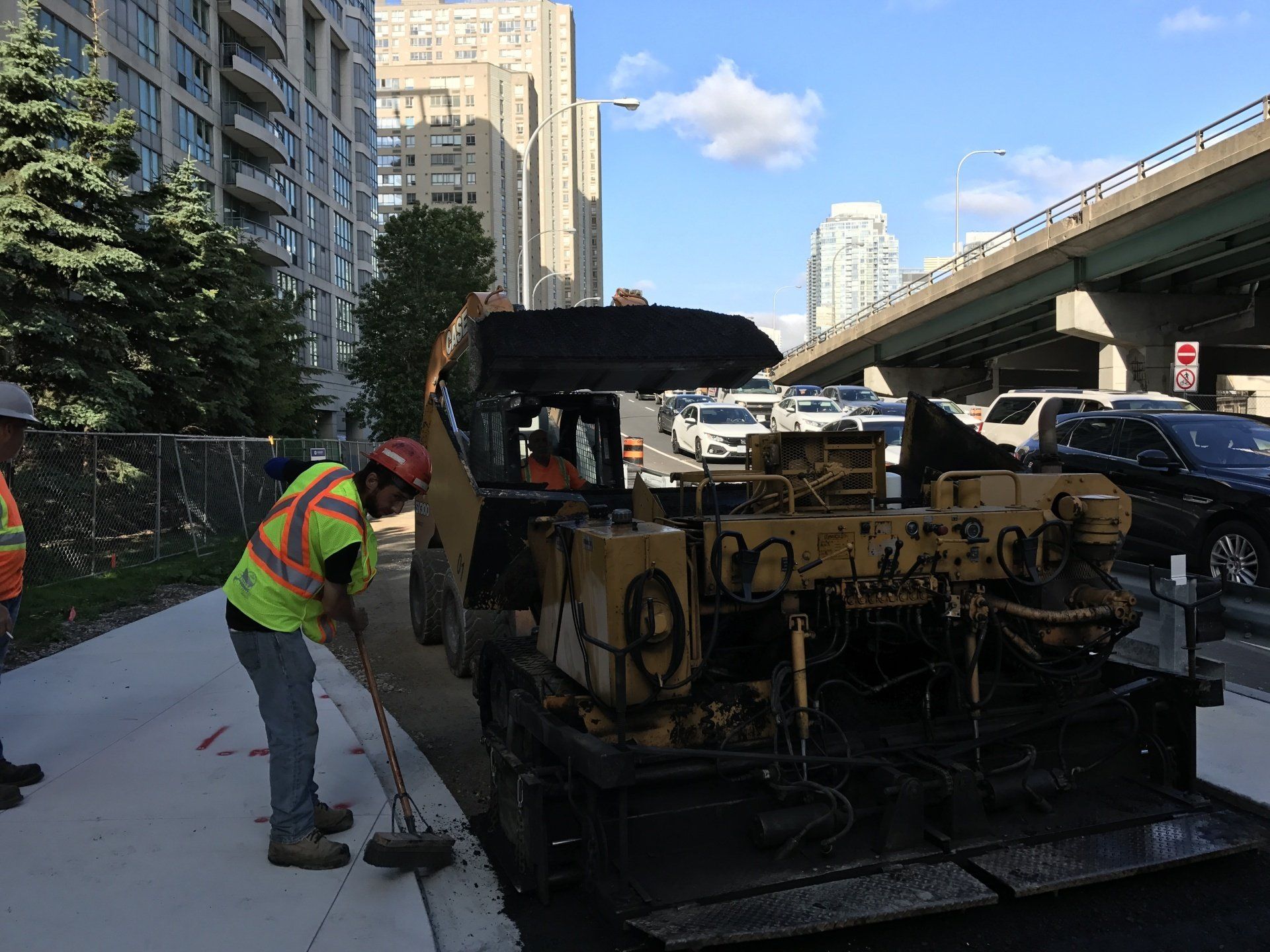 A construction worker is standing next to a bulldozer on the side of the road.
