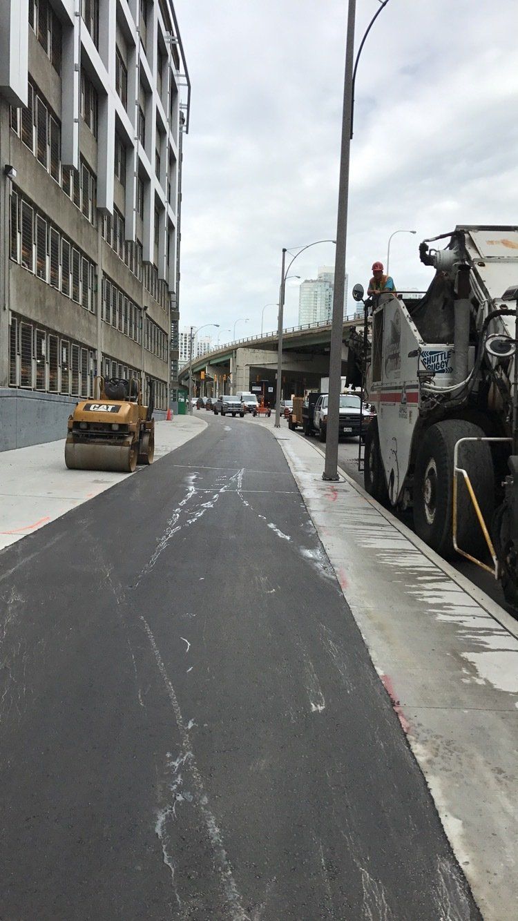 A roller is sitting on the side of a road next to a building.