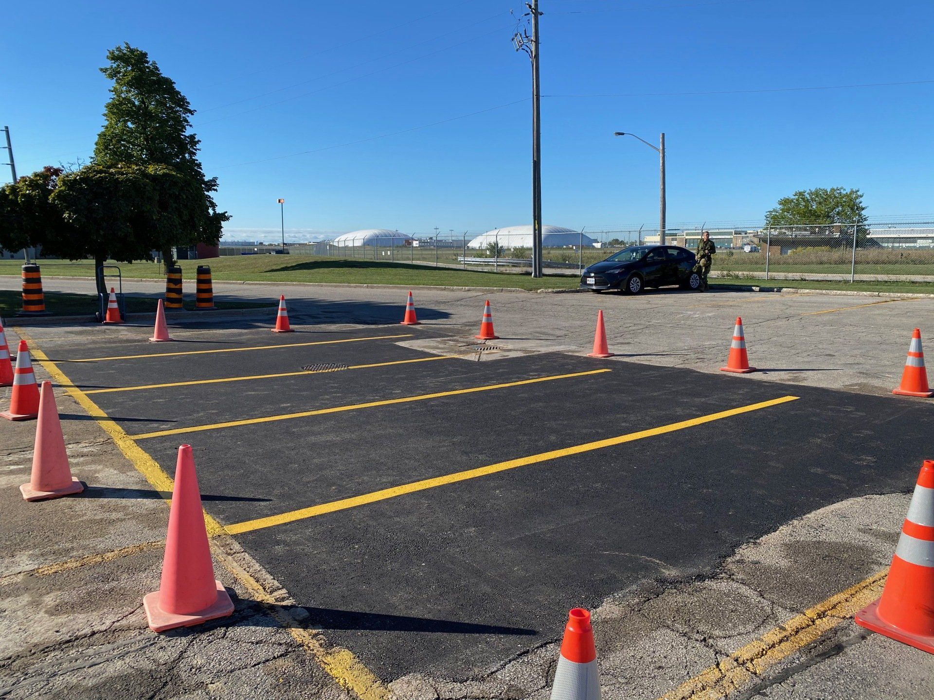 A car is parked in a parking lot surrounded by orange and white traffic cones