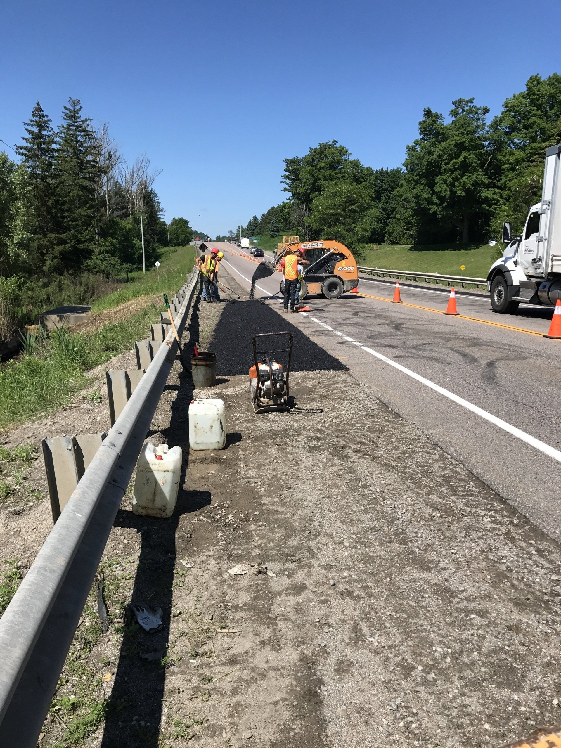 A group of people are working on the side of a highway.