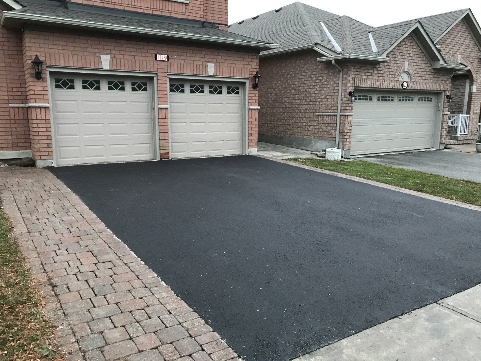 A brick house with two garage doors and a black driveway