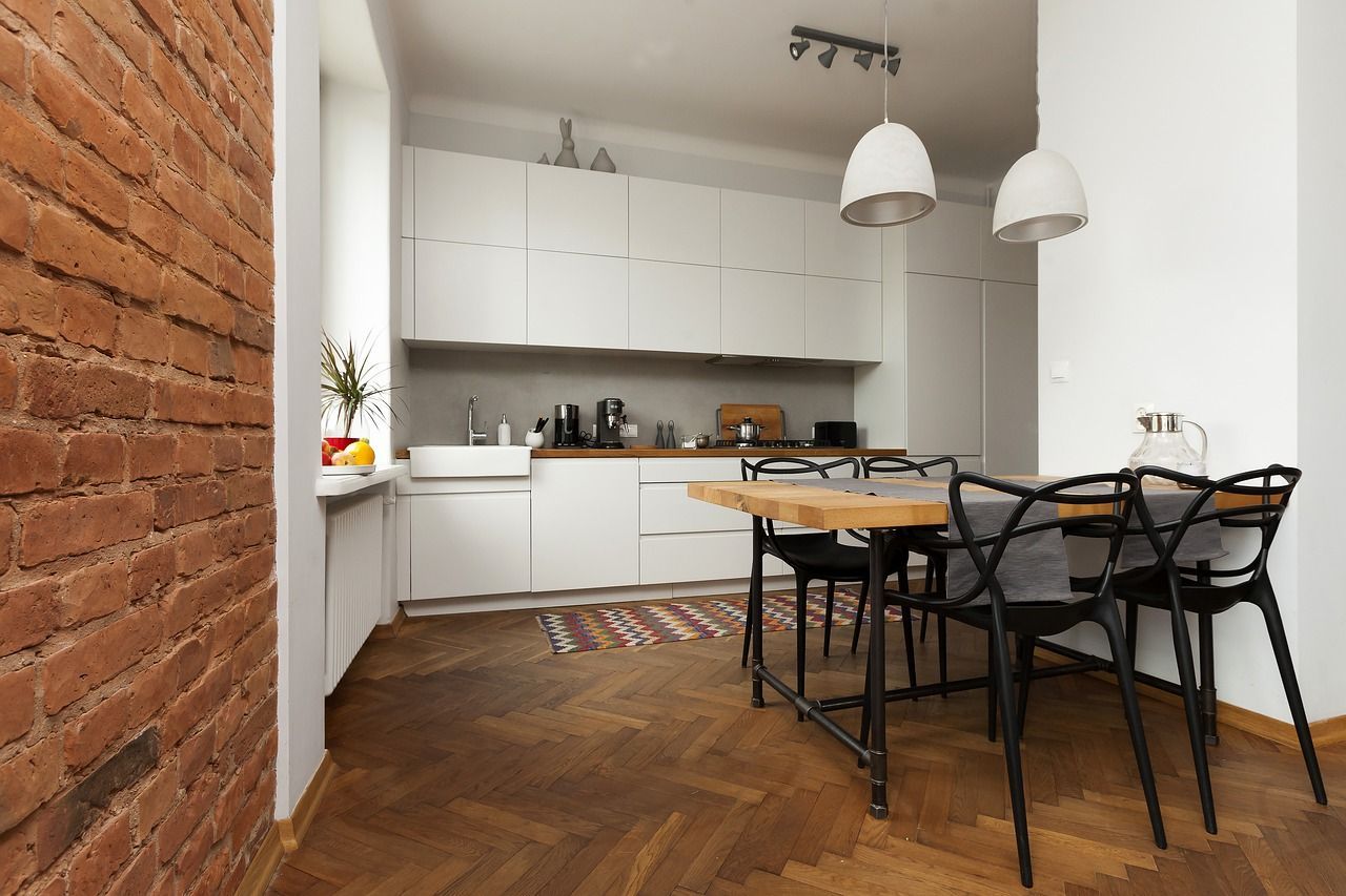 Une cuisine avec une table et des chaises en bois et un mur en briques.