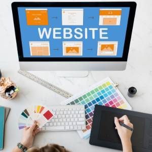 Website design workspace with desktop monitor, color swatches, keyboard, tablet, and tools on a desk