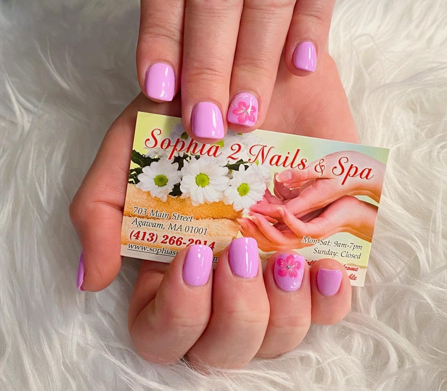 a woman holding a business card for sophia 2 nails & spa