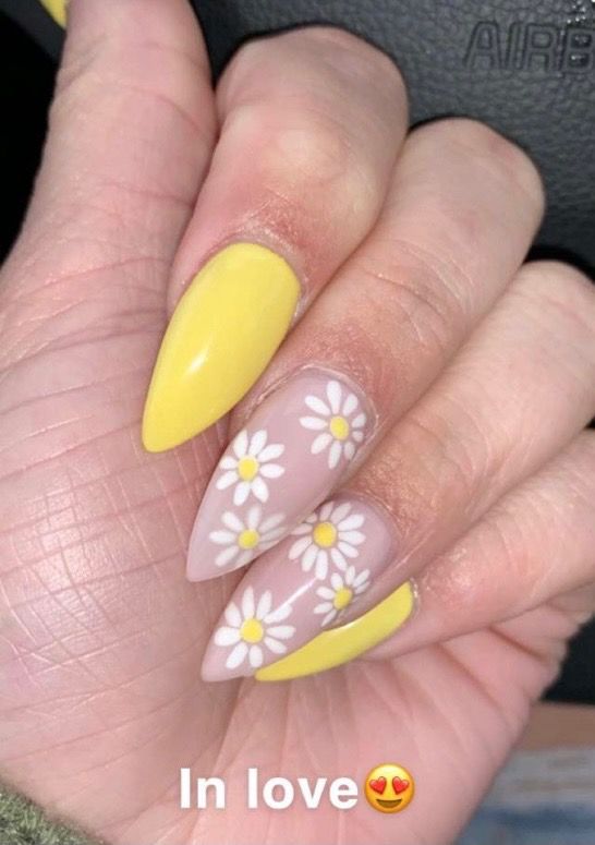 a close up of a person 's nails with yellow and white daisies on them .
