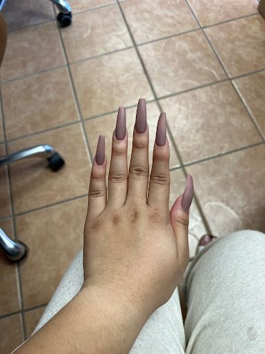 a woman 's hand with long nails is sitting on a tiled floor .