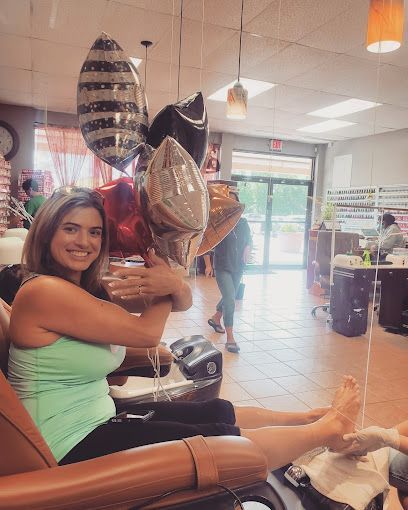 a woman is sitting in a chair in a nail salon holding balloons .