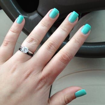 a woman 's hand with blue nails and a ring on her finger .