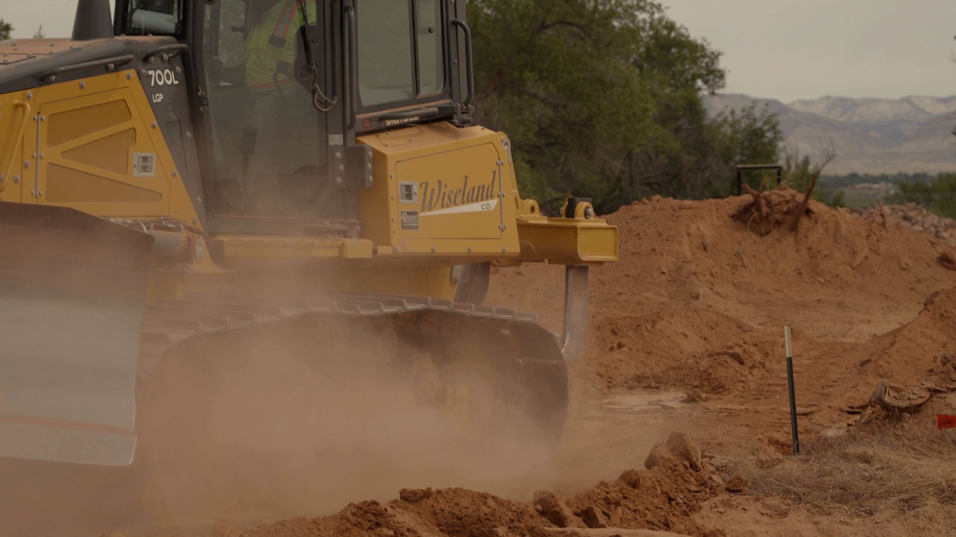 Yellow bulldozer moving dirt at a dusty construction site