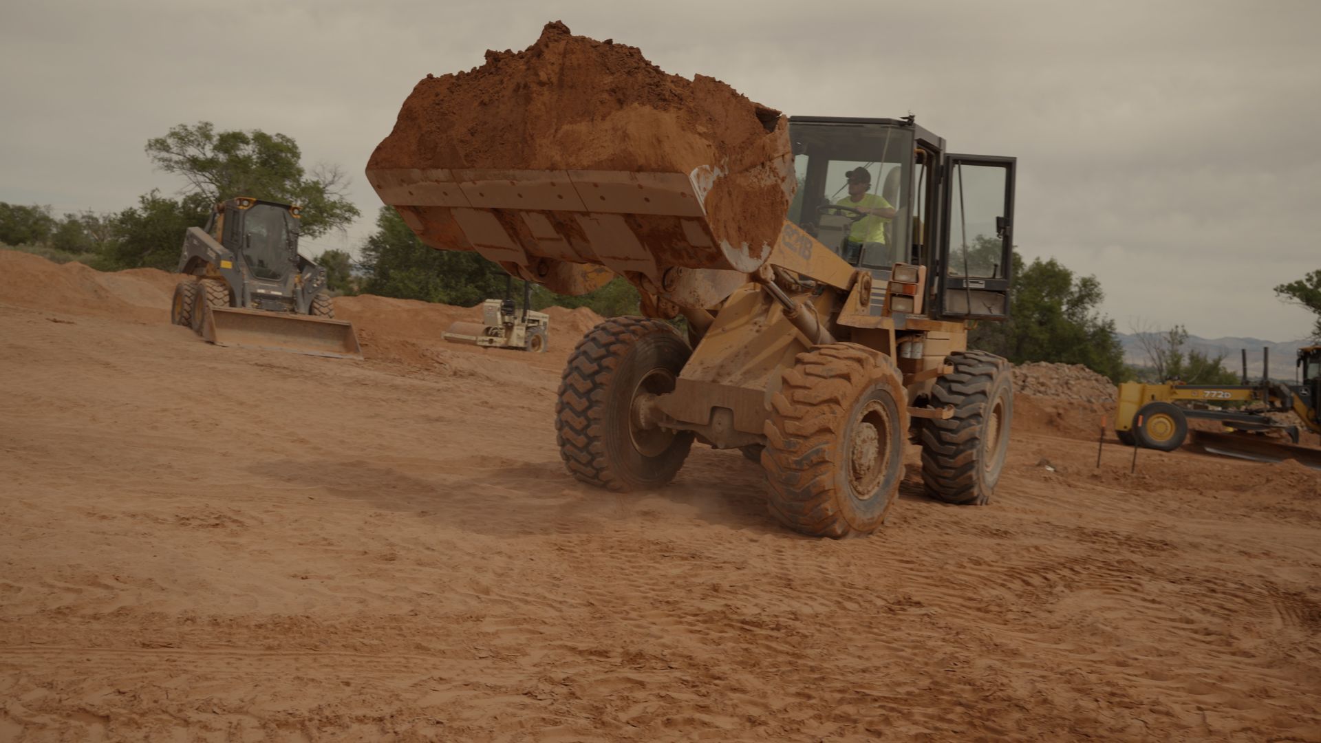 Bulldozer carrying a large load of dirt on a dusty construction site