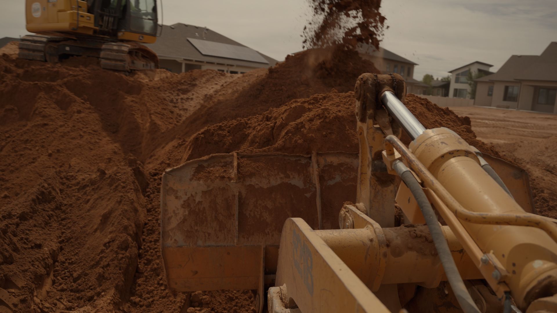 Heavy construction machinery digging red soil at a large excavation site