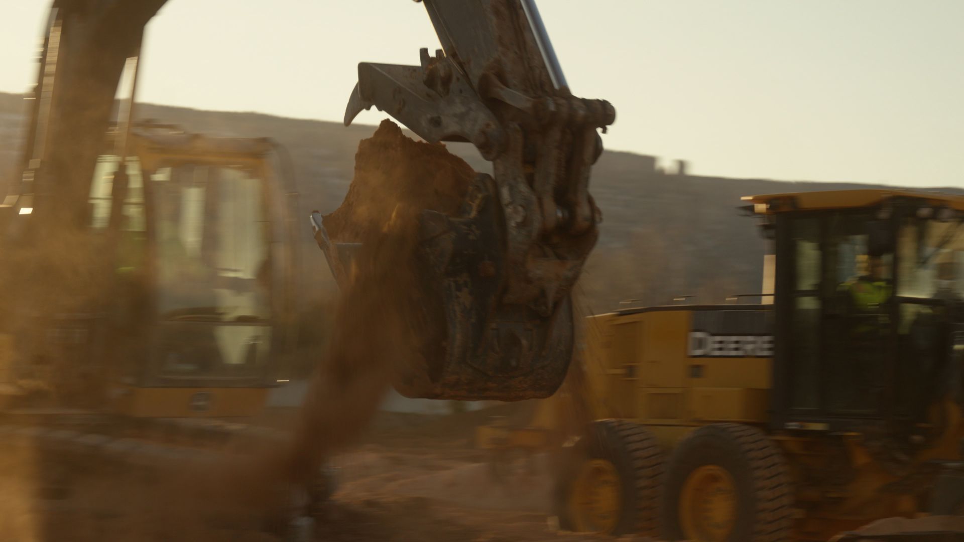 Excavator scooping dirt beside a yellow bulldozer at a dusty construction site