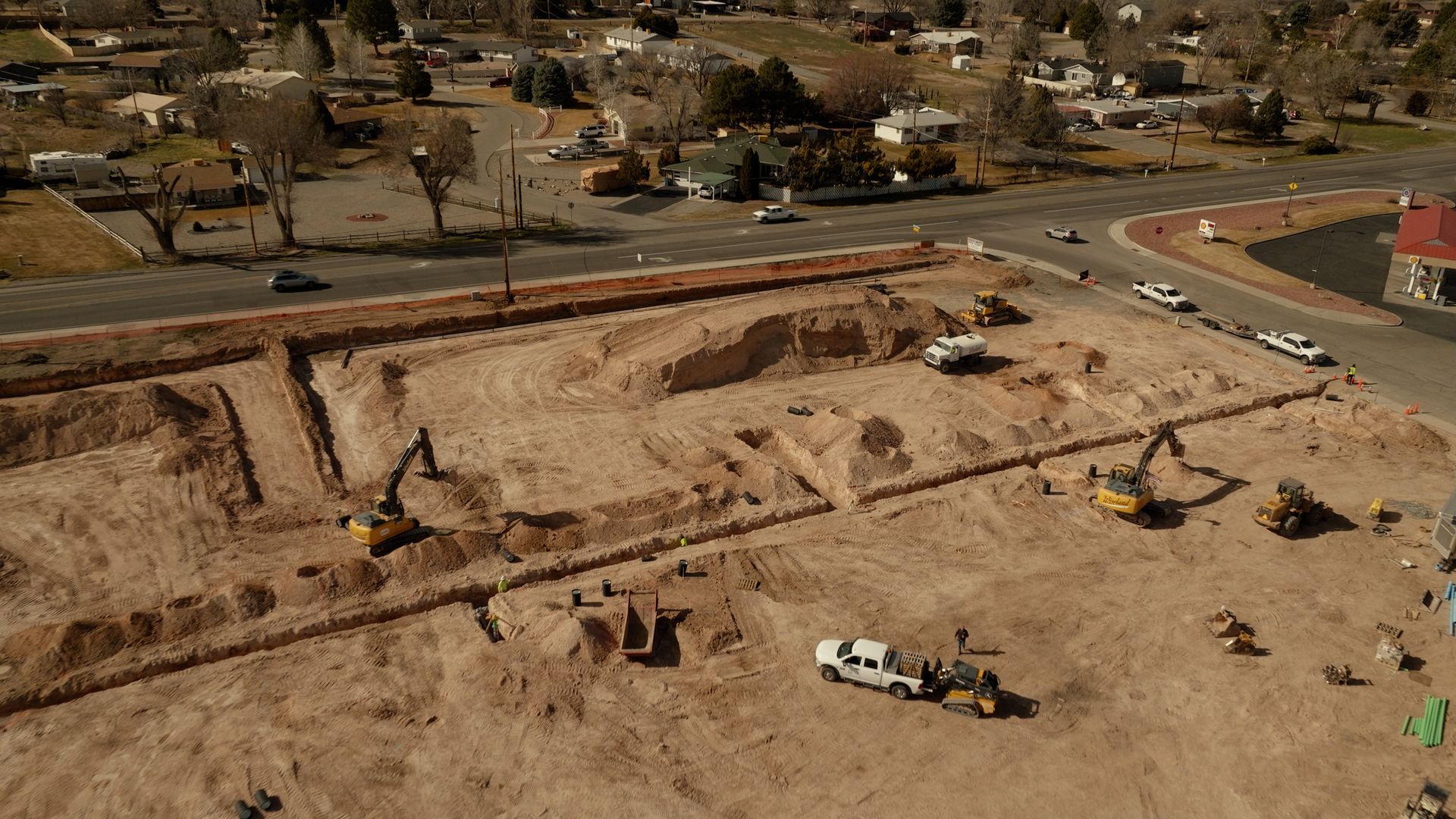 Aerial view of an excavation site with heavy machinery digging at a large construction area.