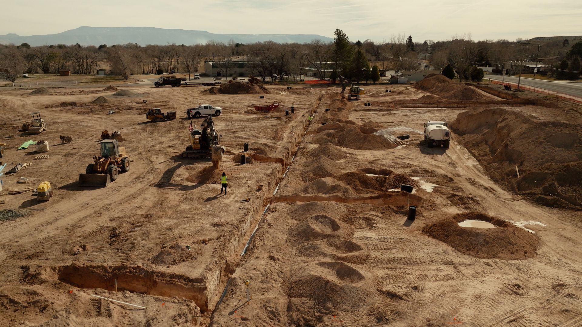 Construction site with excavators and dirt piles under a hazy sky