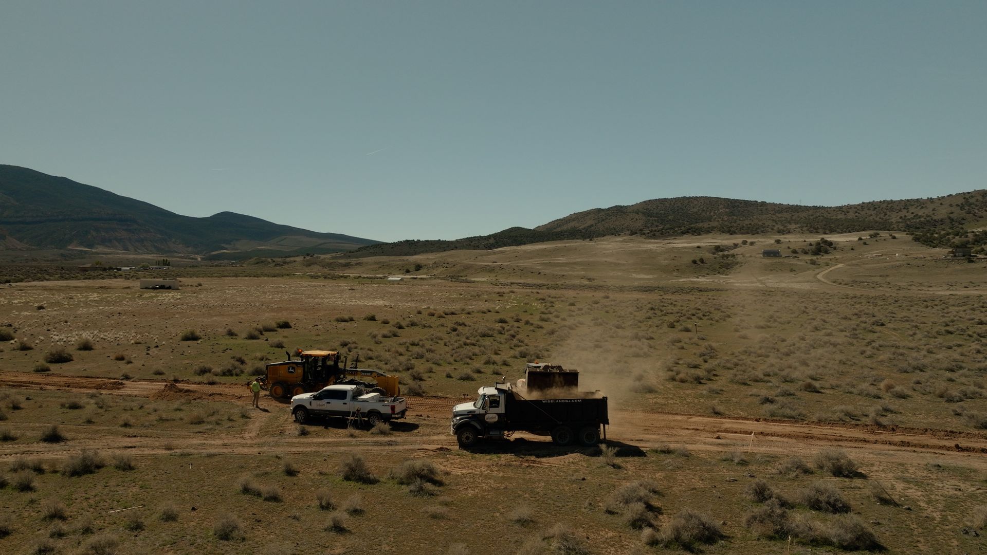 Off-road vehicles parked on a dusty plain with hills in the distance.