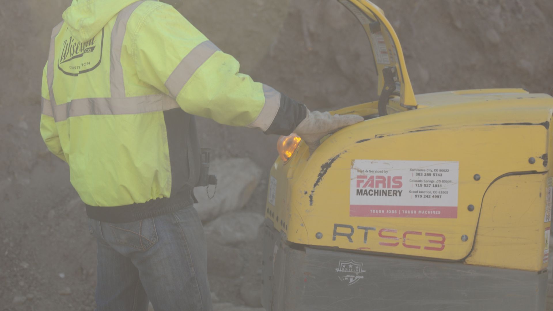 Worker in a neon yellow safety jacket operating a yellow RTS3C machine in a dusty site.