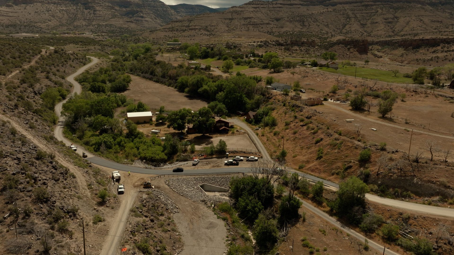 Aerial view of a rural valley with winding roads, scattered houses, and dry hillsides.