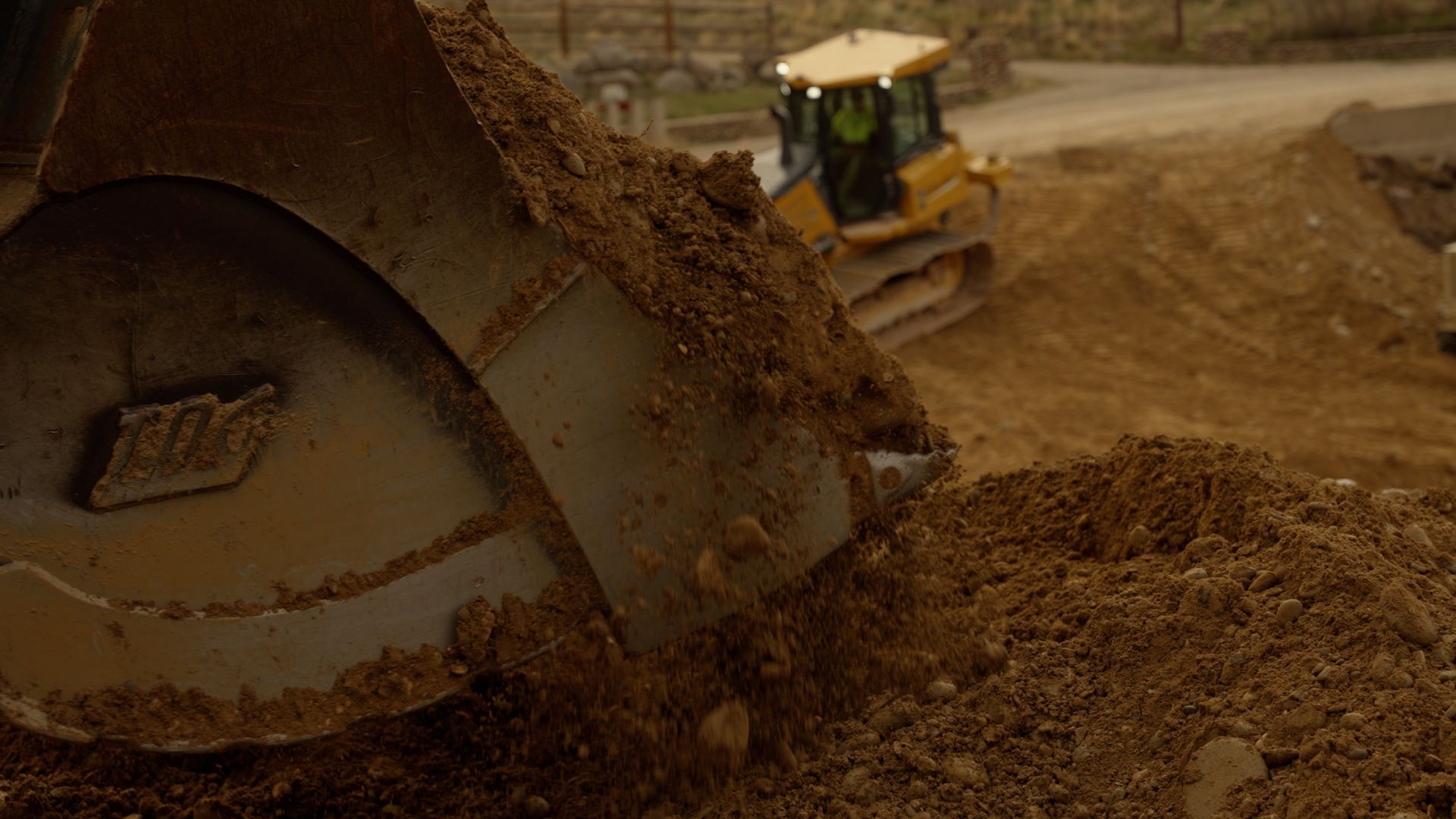 Bulldozer pushing a large pile of dirt at a construction site