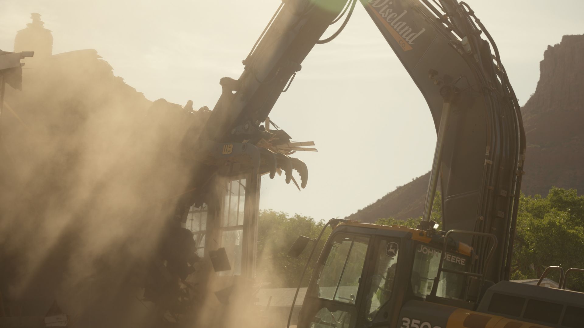 Excavator demolishing a dusty structure in a hazy construction site