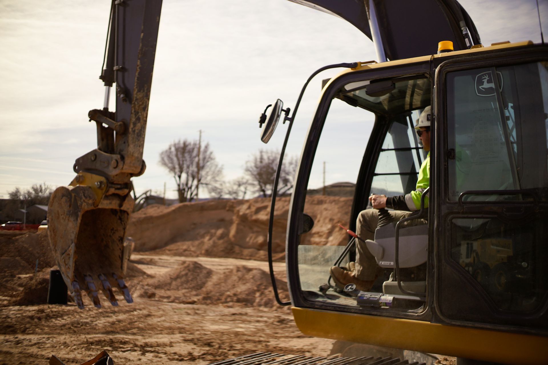 Excavator digging dirt at a construction site, with the cab and bucket in view