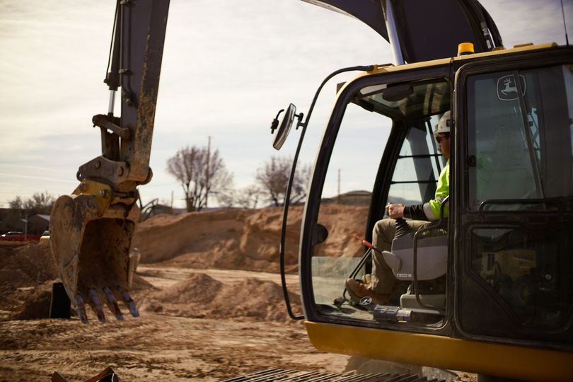 Excavator digging dirt at a construction site, with the cab and bucket in view