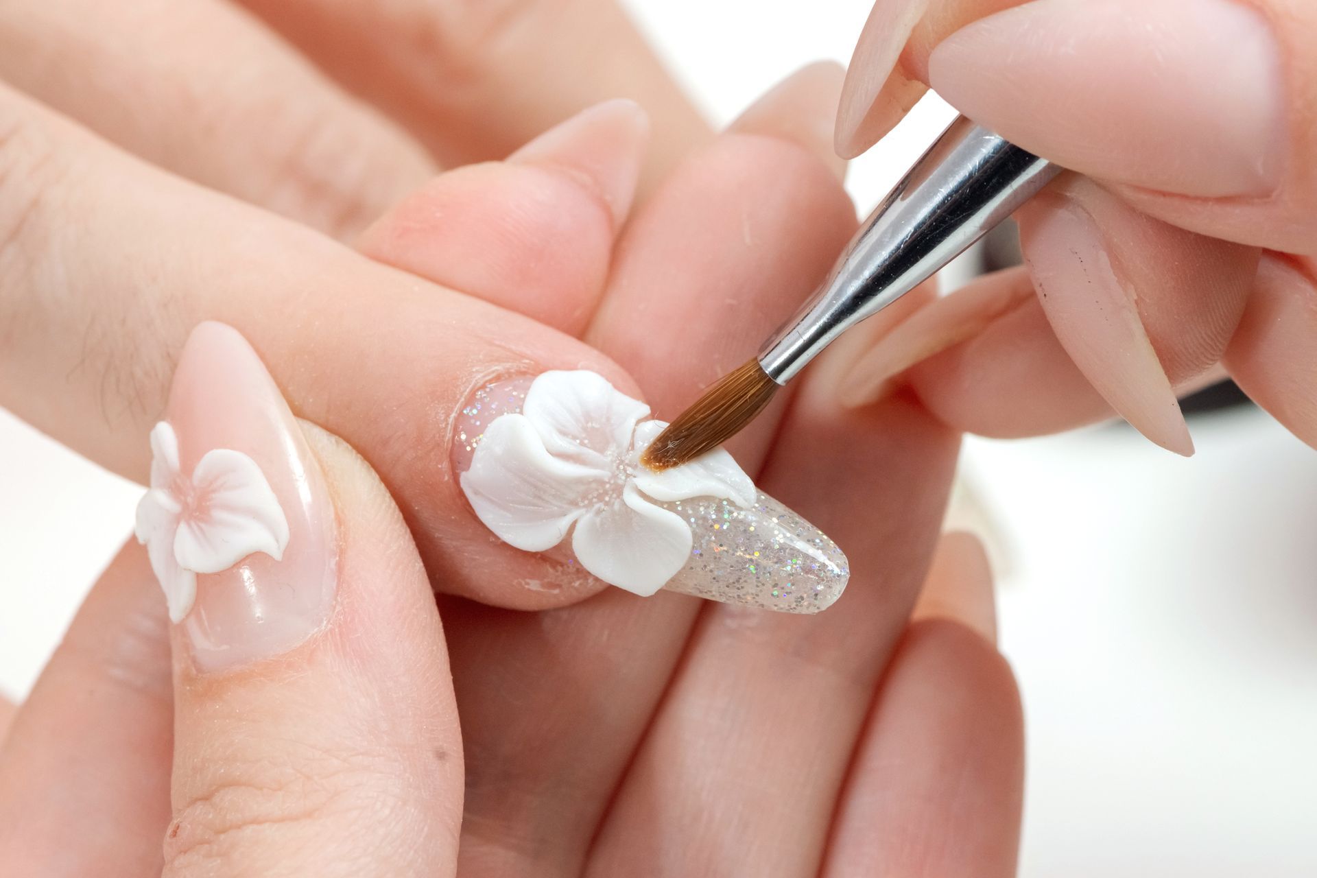 A woman is getting her nails painted with a brush.