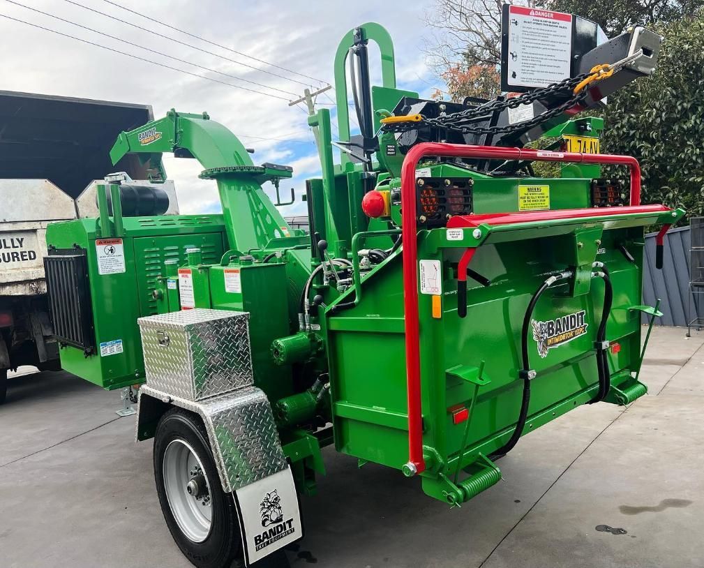 A Green Machine is Parked on the Side of the Road Next to a Truck — Dingo's Tree Services In North Wollongong, NSW