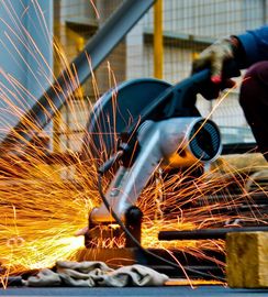 A person is using a grinder to cut a piece of metal