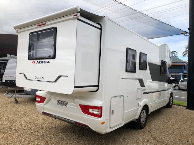 A White Motorhome Is Parked In A Parking Lot Next To A Building — Perkins Caravans in Ballina, NSW