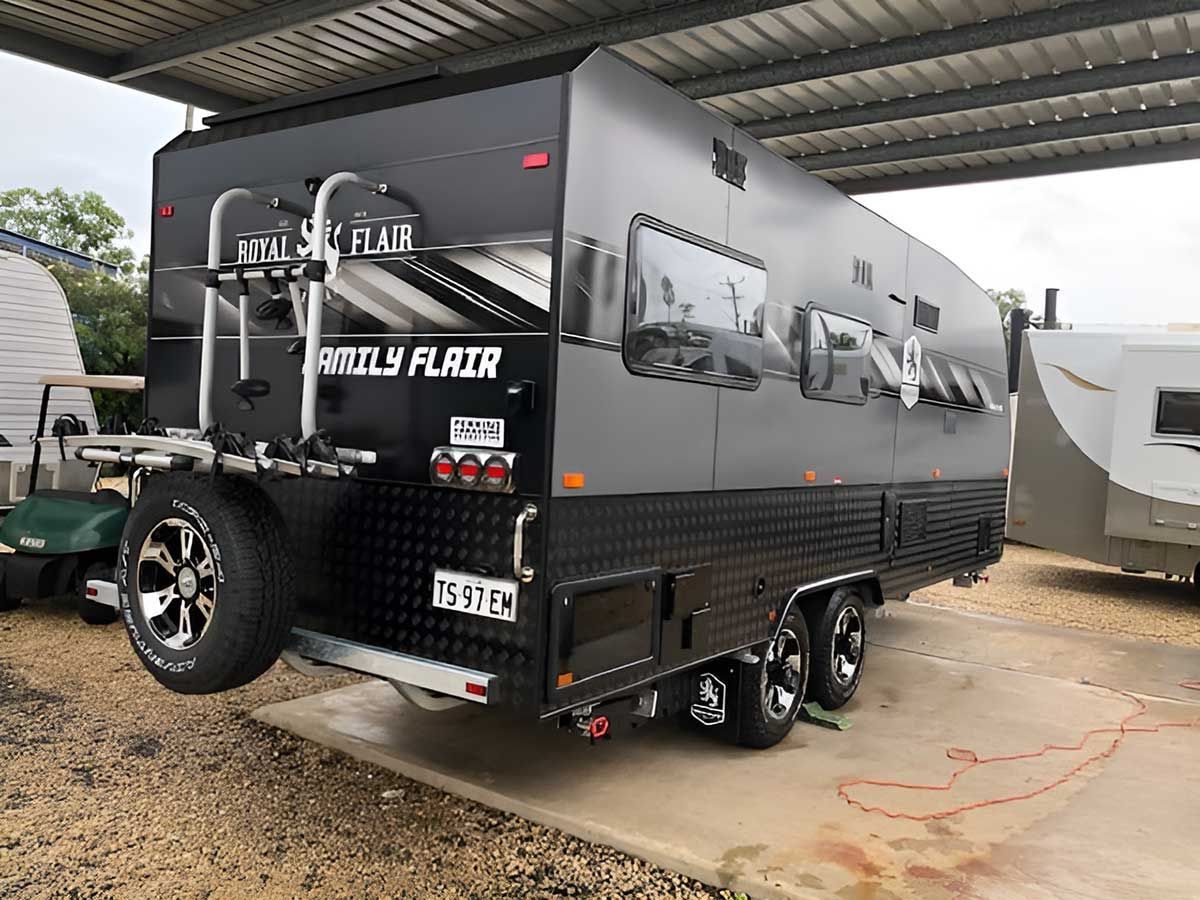 A Black Trailer Is Parked Under A Roof In A Parking Lot — Perkins Caravans in Ballina, NSW
