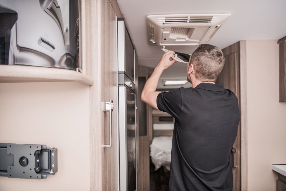 A Man Is Fixing A Ceiling Fan In A Camper — Perkins Caravans in Ballina, NSW