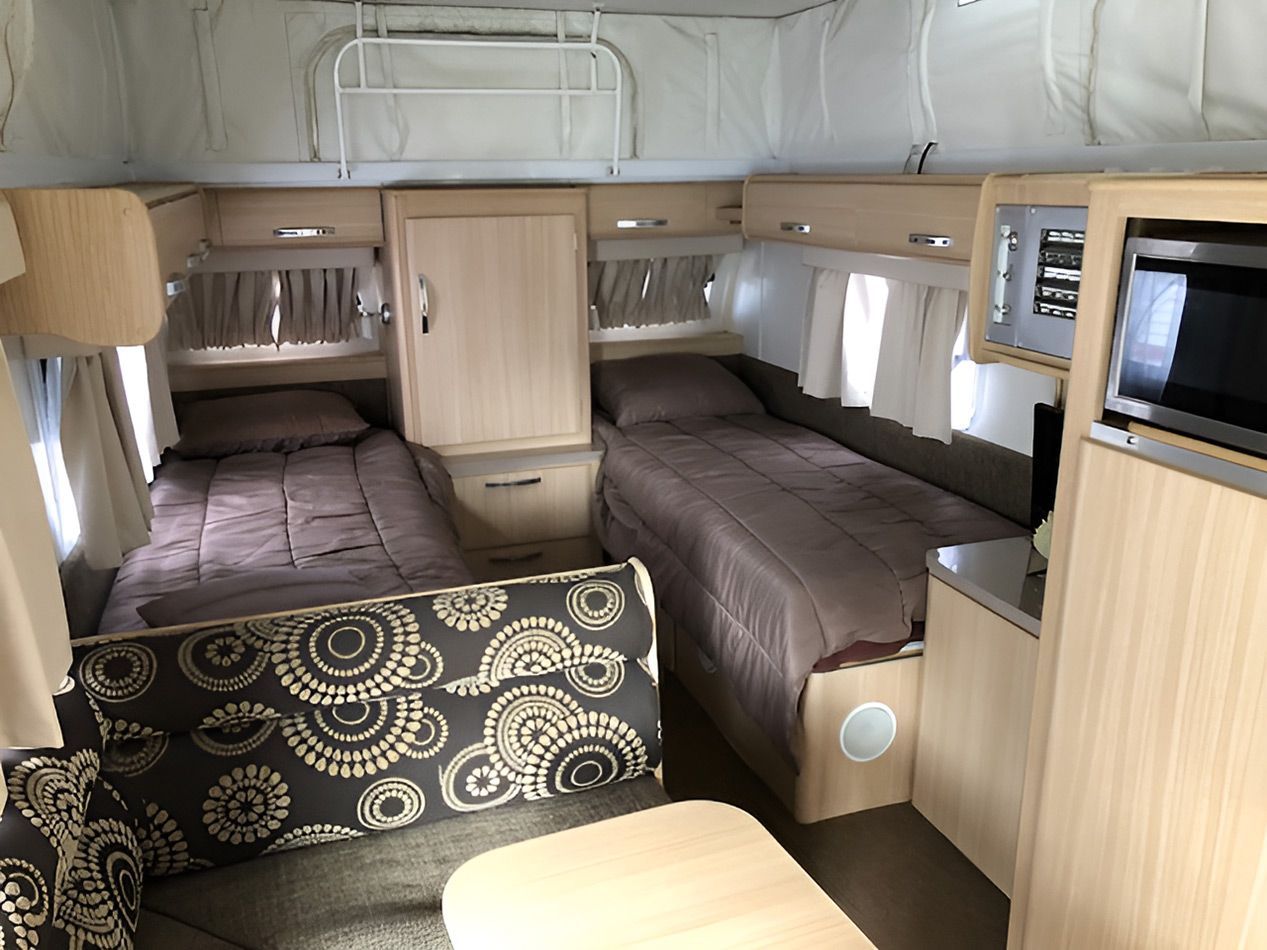 The Inside Of A Camper With Two Beds And A Couch — Perkins Caravans in Byron Bay, NSW