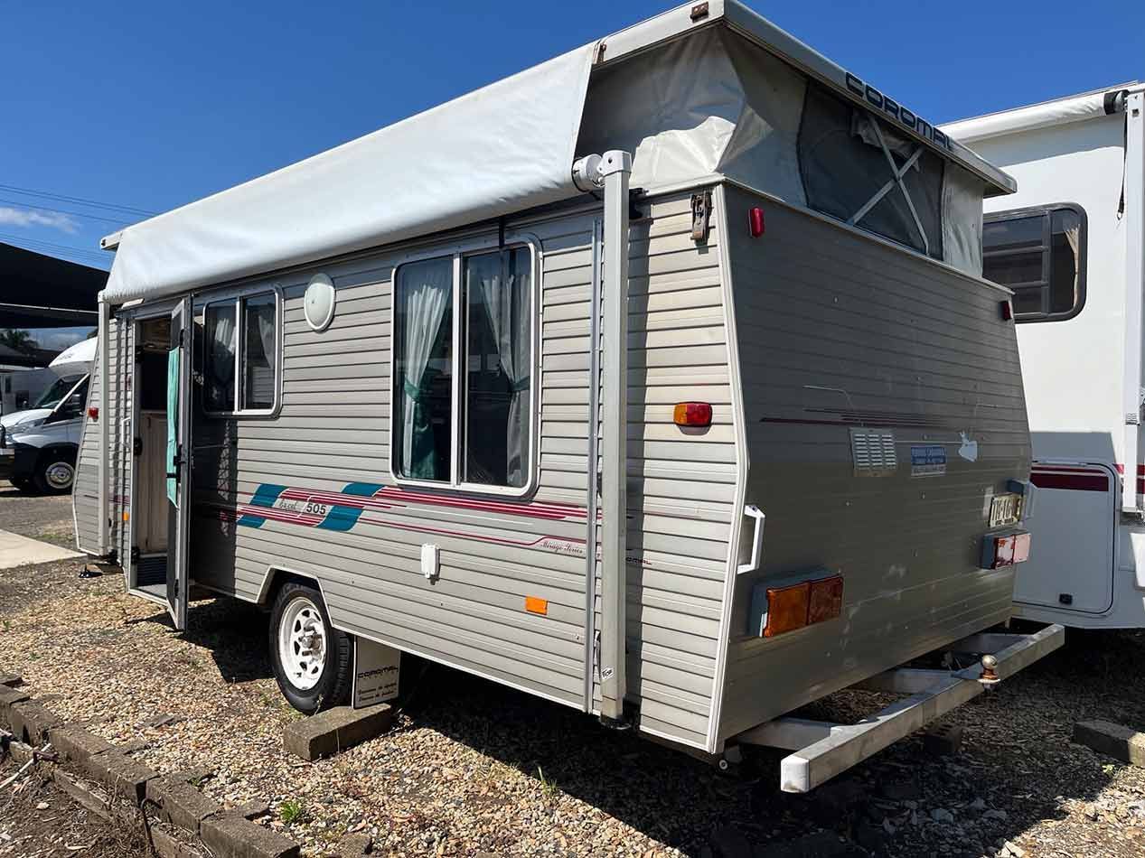 A Small Trailer With A Tent On Top Of It Is Parked In A Gravel Lot — Perkins Caravans in Ballina, NSW