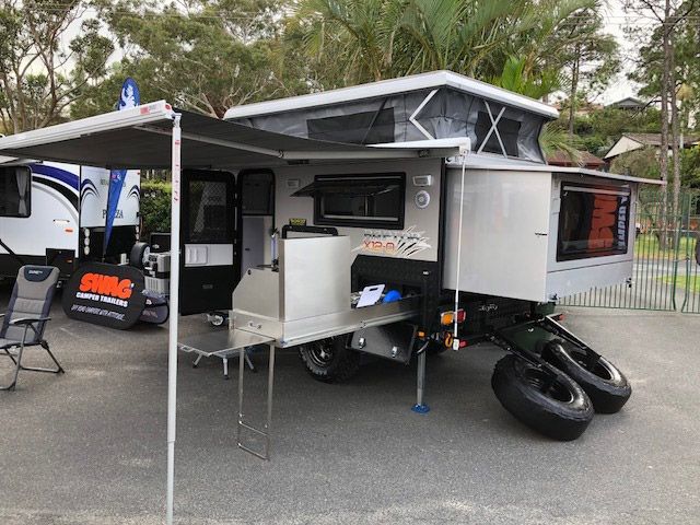 A Camper Trailer With A Rooftop Tent Is Parked In A Parking Lot — Perkins Caravans in Ballina, NSW