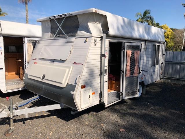A White Trailer With A Tent On Top Of It Is Parked In A Parking Lot — Perkins Caravans in Ballina, NSW