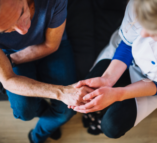 Two people holding hands in a comforting gesture indoors