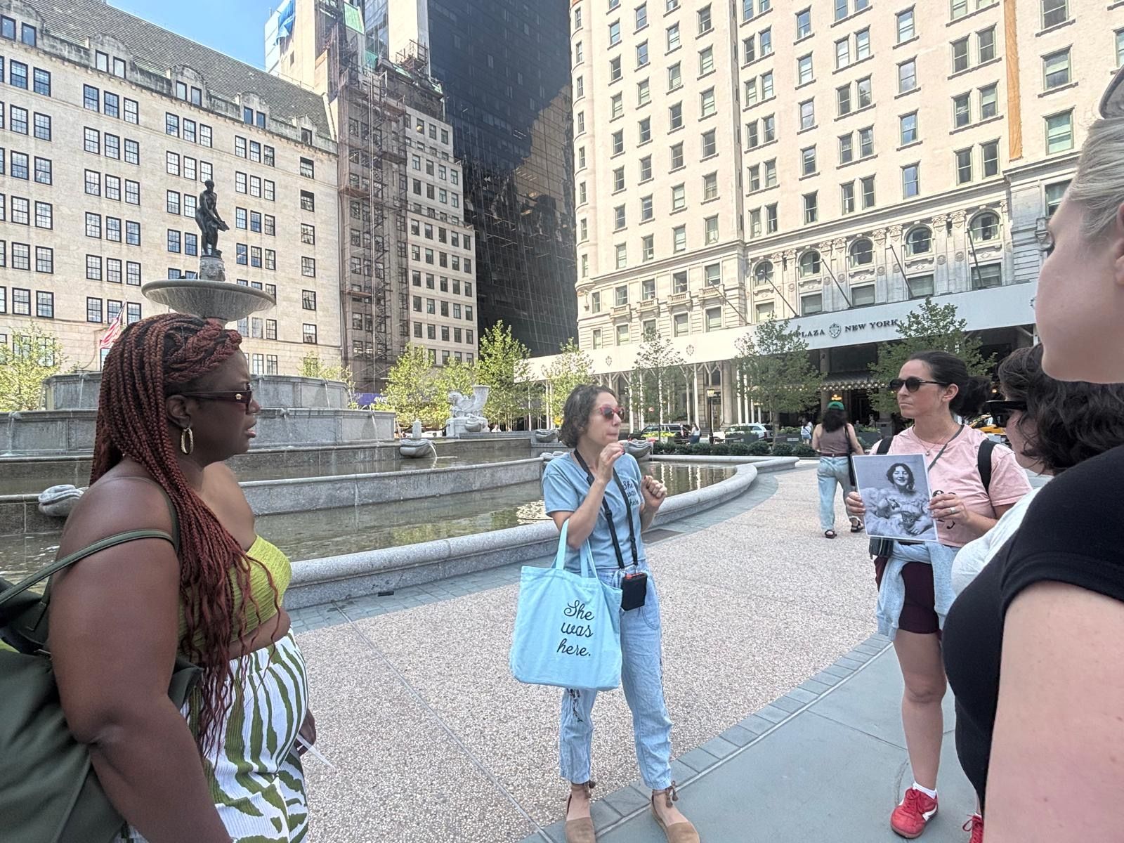 Tour group listens to NYC women's history in front of Plaza Hotel.
